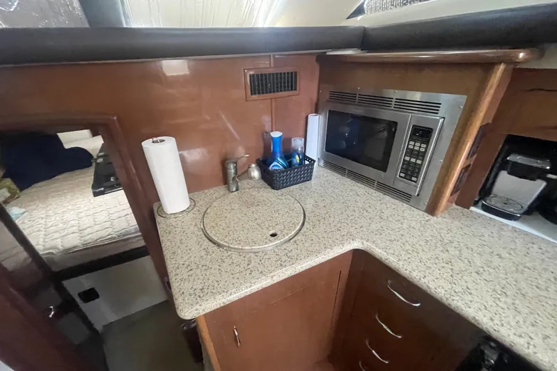 Slide: The Image of 2008 Carver 41 Cockpit Motor Yacht kitchen with microwave, sink, and countertop essentials. - 24