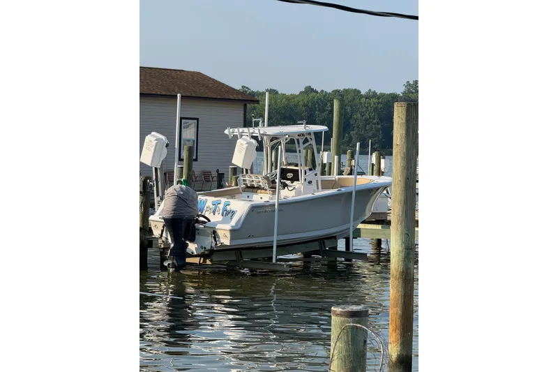 Slide: The Image of 2018 Sportsman Open 232 Center Console boat docked at marina with person working on it. - 13