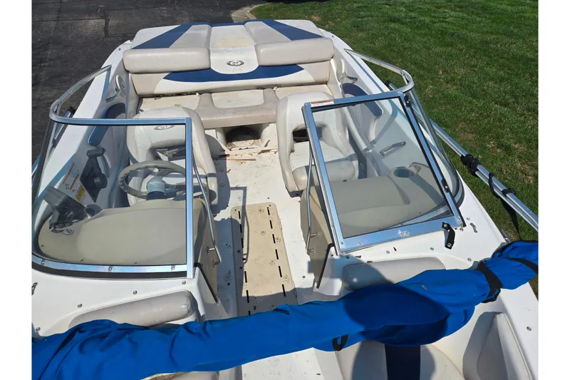 Slide: The Image of 2007 Glastron GT 185 boat interior with seating and steering wheel, parked on grass. - 20