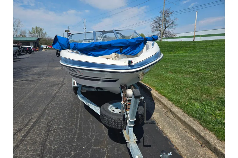 Slide: The Image of 2007 Glastron GT 185 boat on trailer with blue cover, parked on asphalt. - 6