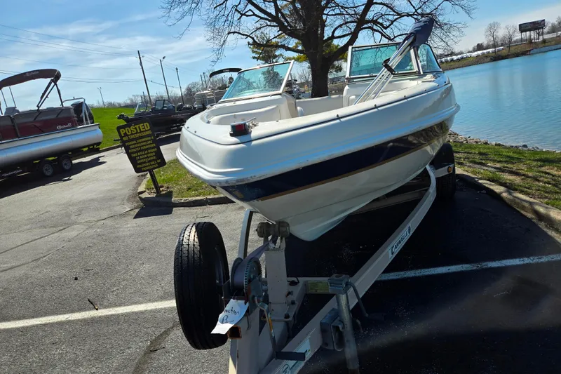 Slide: The Image of 2001 Caravelle 188 Bow Rider boat on trailer by a lakeside parking area. - 6