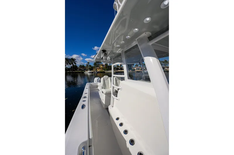 Slide: The Image of 2021 Invincible 39 Open Fisherman boat, sleek design, docked by palm trees under clear blue sky. - 27
