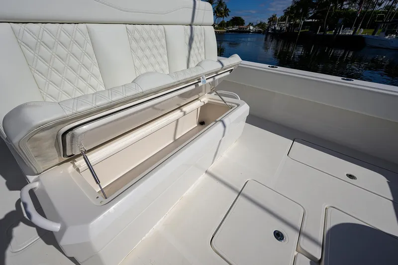 Slide: The Image of 2021 Invincible 39 Open Fisherman boat with open storage compartment, white seating, and waterfront view. - 55