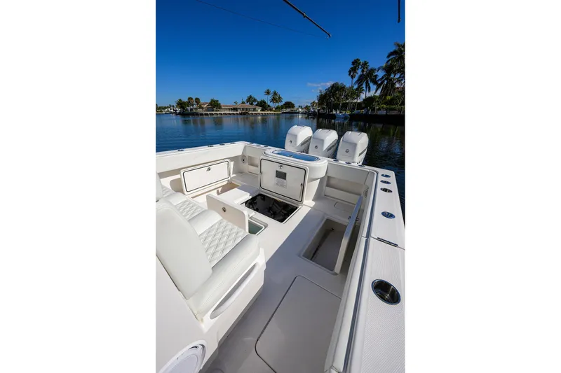 Slide: The Image of 2021 Invincible 39 Open Fisherman boat interior with seating and storage, docked by palm trees. - 57