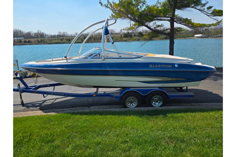 Slide: The Image of 2005 Glastron GX 235 boat on trailer by a lake, under a tree. - 10