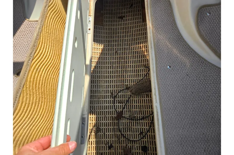 Slide: The Image of 2005 Glastron GX 235 boat interior storage compartment with carpet and debris. - 15
