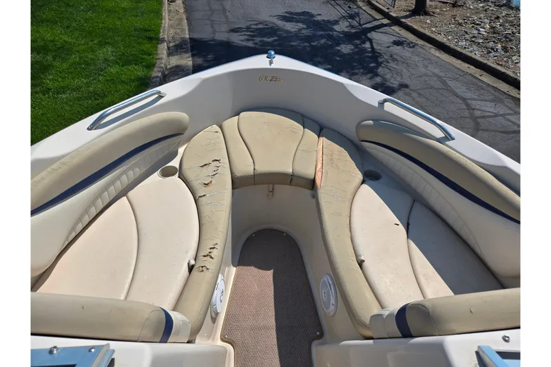 Slide: The Image of 2005 Glastron GX 235 boat interior with worn beige seating and carpeted floor. - 17