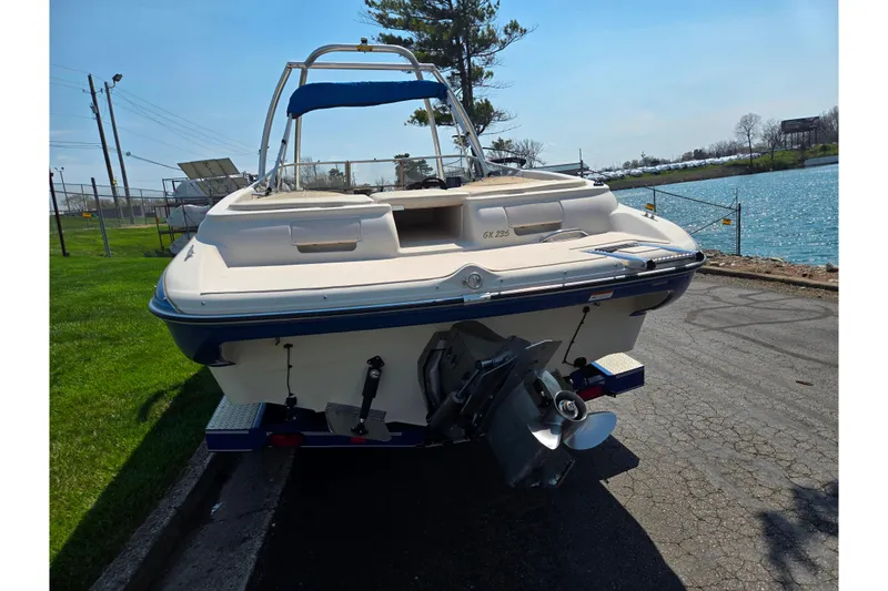 Slide: The Image of 2005 Glastron GX 235 boat parked near a lake on a sunny day. - 2