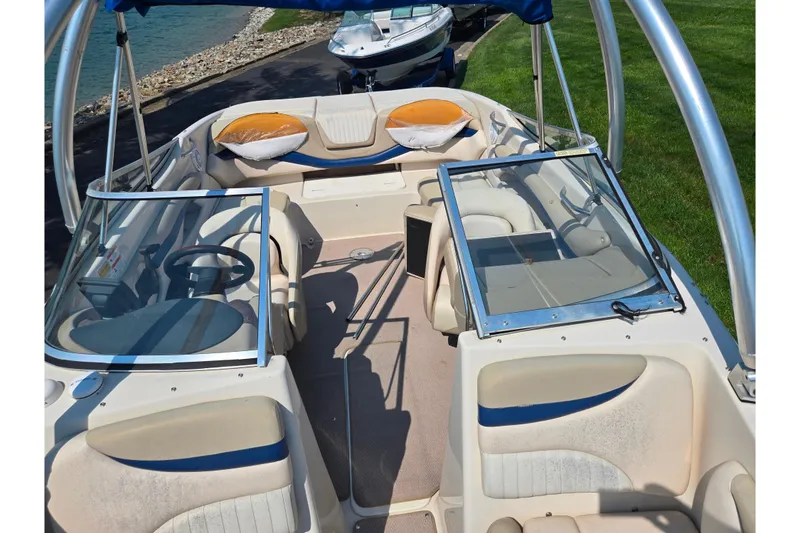 Slide: The Image of 2005 Glastron GX 235 boat interior with seating and steering wheel, docked by a lake. - 20