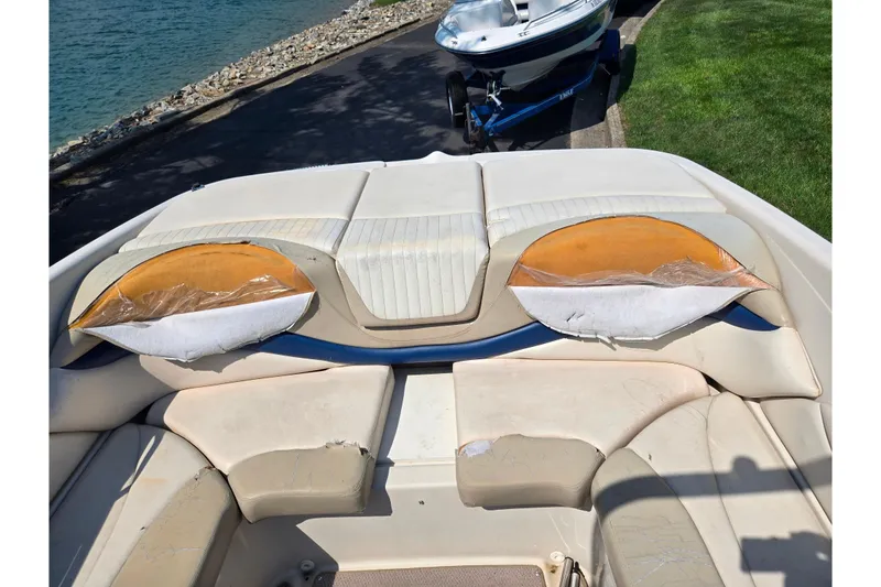 Slide: The Image of 2005 Glastron GX 235 boat interior with worn upholstery near a lakeside. - 22