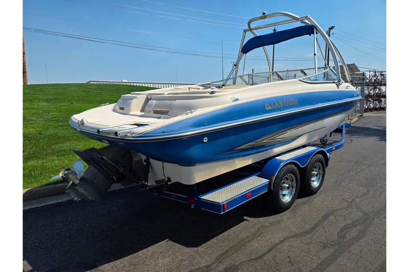 Slide: The Image of 2005 Glastron GX 235 boat on trailer, blue and white design, parked outdoors. - 3
