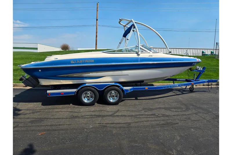 Slide: The Image of 2005 Glastron GX 235 boat on trailer, blue and white design, parked outdoors. - 4