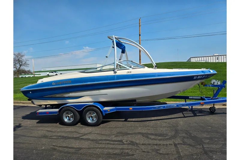Slide: The Image of 2005 Glastron GX 235 boat on trailer, blue and white design, parked outdoors. - 5
