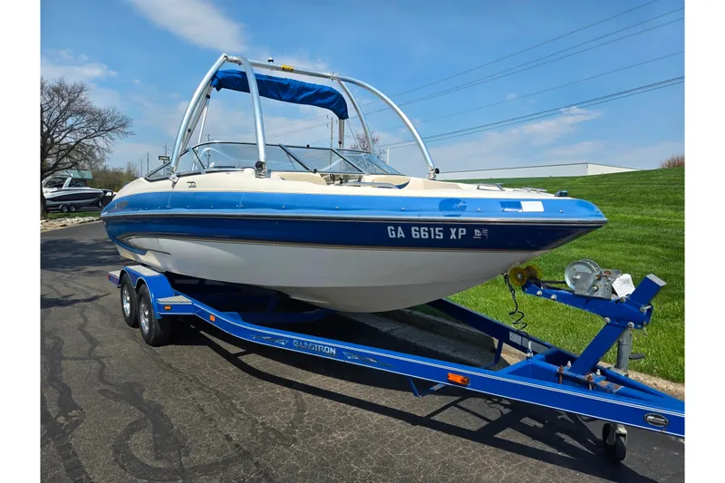 Slide: The Image of 2005 Glastron GX 235 boat on trailer, blue and white, parked on asphalt. - 6