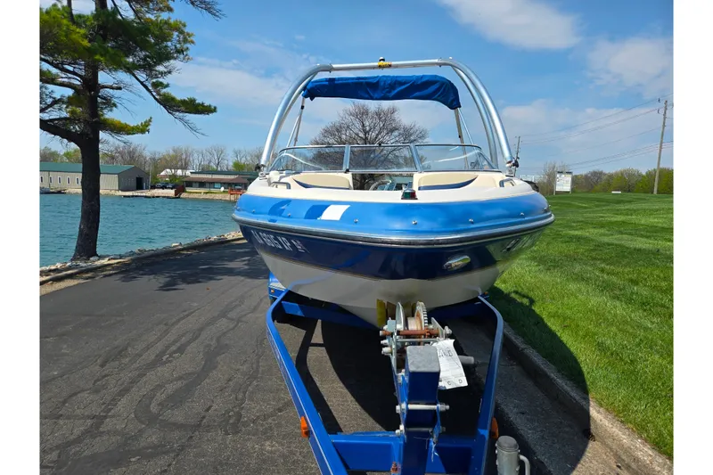 Slide: The Image of 2005 Glastron GX 235 boat on trailer by a lakeside road. - 7
