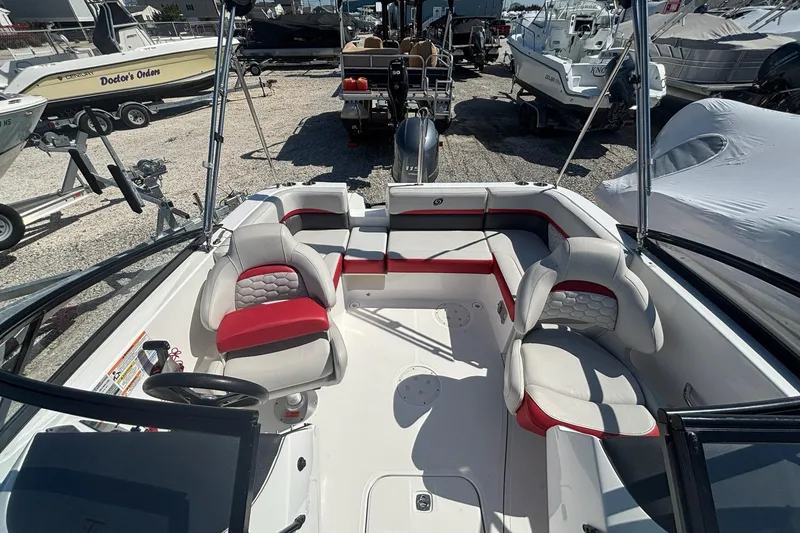 Slide: The Image of 2020 Hurricane SunDeck 191 OB boat interior with red and white seating, docked among other boats. - 11