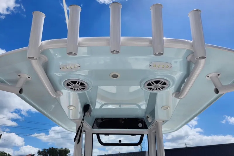 Slide: The Image of 2024 Sportsman Open 232 Center Console T-top with rod holders and speakers under blue sky. - 29