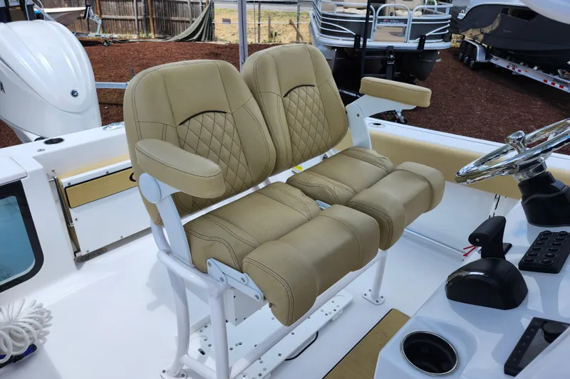 Slide: The Image of 2024 Sportsman Open 232 Center Console boat with tan cushioned seating and steering wheel. - 32