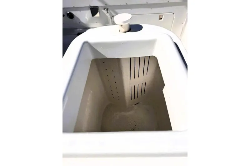 Slide: The Image of Livewell compartment in a 1991 Bertram 28 boat, featuring a white interior and drainage slots. - 23