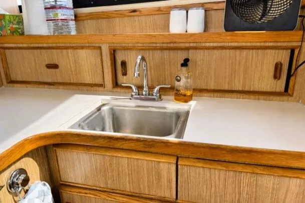 Slide: The Image of Kitchen area of a 1991 Bertram 28 boat with wooden cabinetry and stainless steel sink. - 25