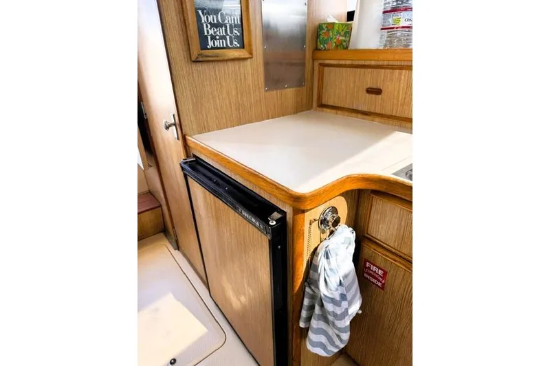 Slide: The Image of Interior of a 1991 Bertram 28 boat with wooden cabinetry and compact kitchen area. - 27
