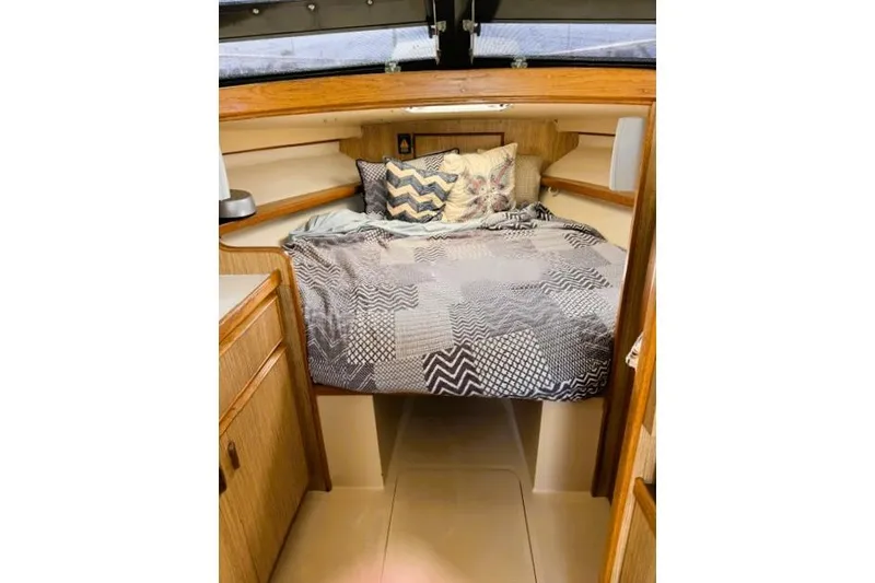 Slide: The Image of Cozy cabin interior of a 1991 Bertram 28 boat with patterned bedding. - 28