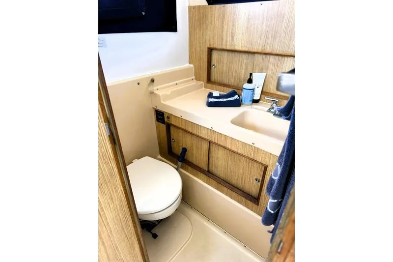 Slide: The Image of 1991 Bertram 28 boat bathroom with sink, toilet, and wooden cabinetry. - 30