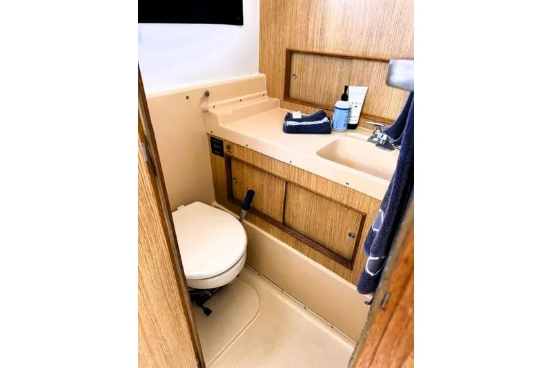 Slide: The Image of 1991 Bertram 28 boat bathroom with wooden cabinetry and compact sink area. - 31