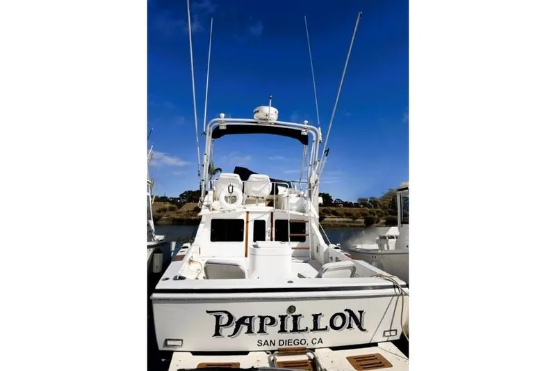 Slide: The Image of 1991 Bertram 28 boat named "Papillon" docked in San Diego, CA, under clear blue skies. - 32