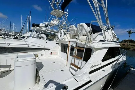 Slide: The Image of 1991 Bertram 28 boat docked at marina, featuring spacious deck and flybridge. - 5