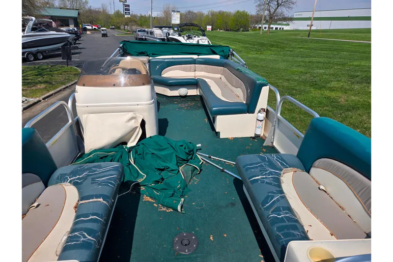 Slide: The Image of 1998 Starcraft pontoon boat with worn seating and green carpet, parked outdoors. - 10