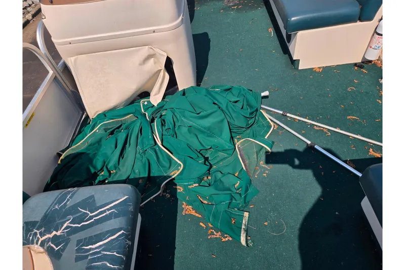 Slide: The Image of 1998 Starcraft boat interior with green tarp and metal poles on carpeted floor. - 11