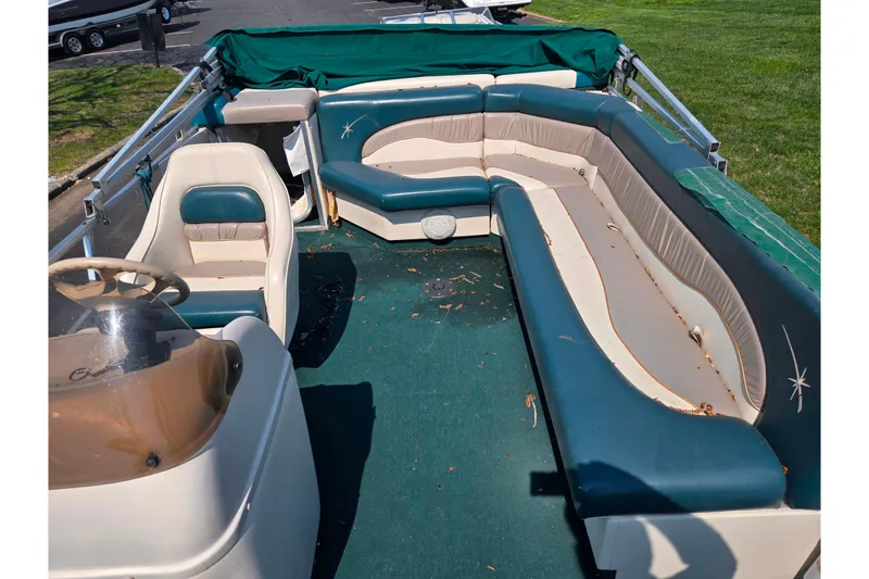 Slide: The Image of 1998 Starcraft boat interior with green and beige seating, steering wheel, and carpet. - 13