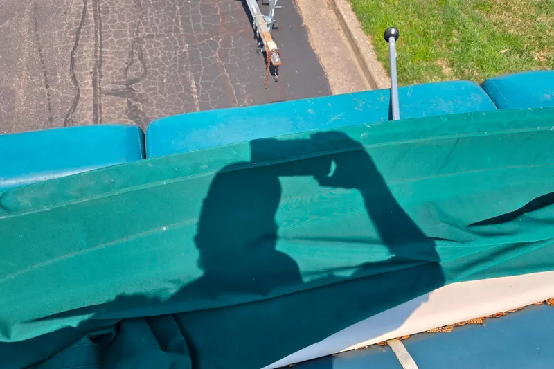 Slide: The Image of Shadow on green fabric of a 1998 Starcraft boat, with pavement and grass visible. - 15