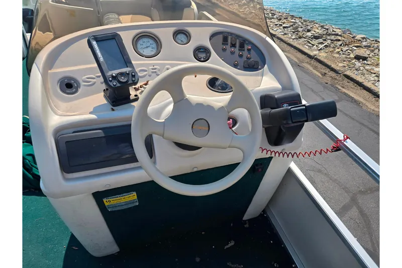 Slide: The Image of 1998 Starcraft boat dashboard with steering wheel, gauges, and navigation device by the water. - 18