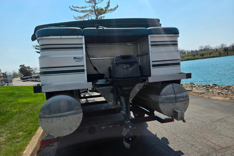 Slide: The Image of 1998 Starcraft pontoon boat on trailer by a lake, featuring outboard motor. - 2