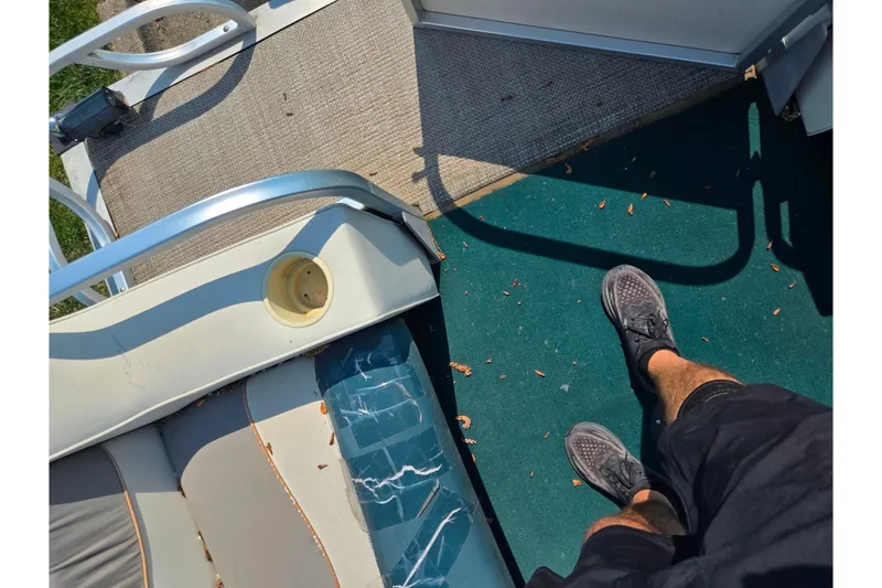 Slide: The Image of Man standing on a 1998 Starcraft boat deck with green carpet and seating. - 22