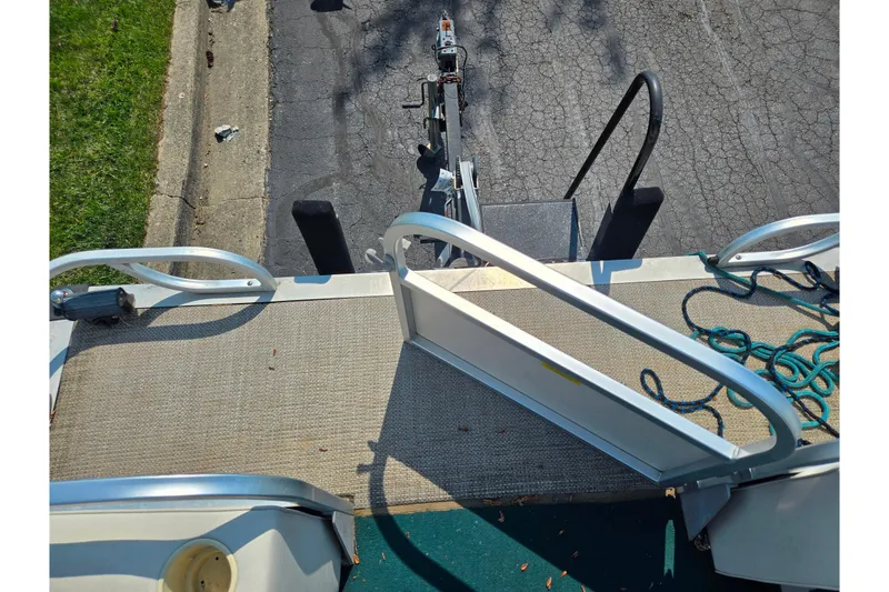 Slide: The Image of 1998 Starcraft boat trailer with ramp and coiled rope on pavement. - 23