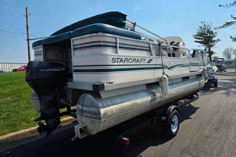 Slide: The Image of 1998 Starcraft pontoon boat on trailer, parked outdoors under clear sky. - 3