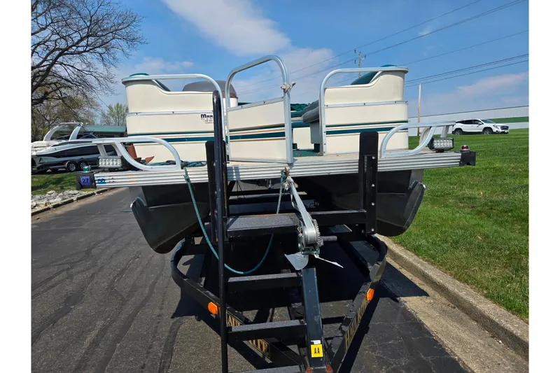 Slide: The Image of 1998 Starcraft pontoon boat on trailer, parked on asphalt near grassy area. - 6