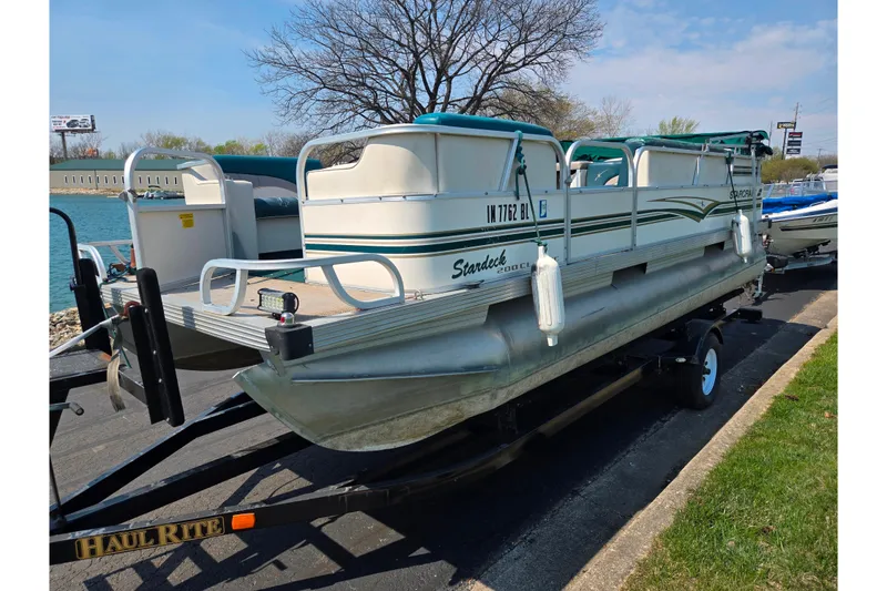Slide: The Image of 1998 Starcraft pontoon boat on trailer by a lake, ready for transport. - 8