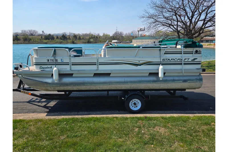 Slide: The Image of 1998 Starcraft pontoon boat on trailer by a lake, ready for transport. - 9