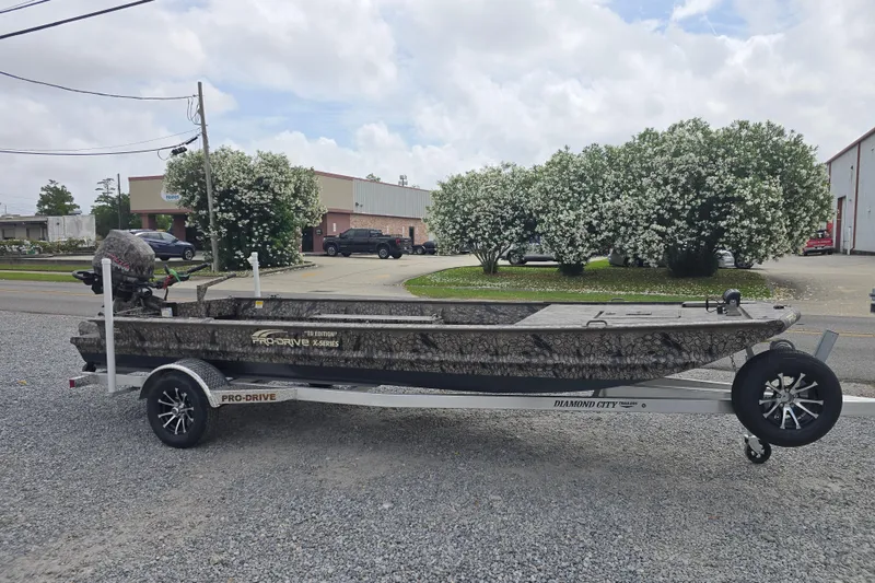 Slide: The Image of Pro-Drive 2060 boat on trailer, camo design, parked outdoors, 2026 model. - 2