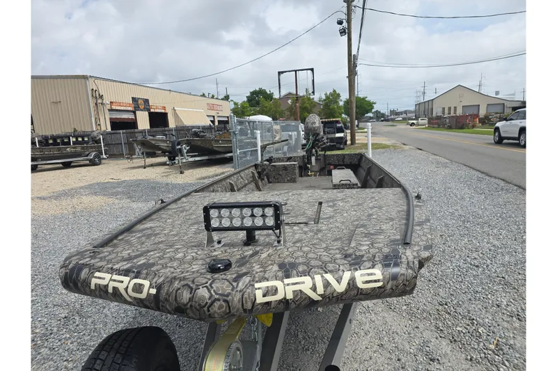 Slide: The Image of 2026 Pro-Drive 2060 boat with camouflage design, parked on gravel near industrial buildings. - 9