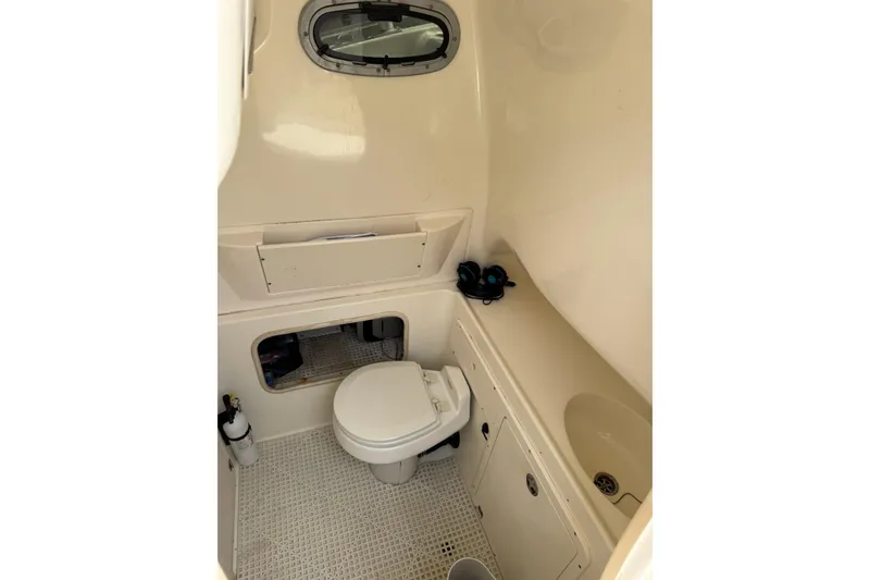 Slide: The Image of 2006 Boston Whaler 320 Outrage Cuddy Cabin interior with beige seating and storage compartments. - 11