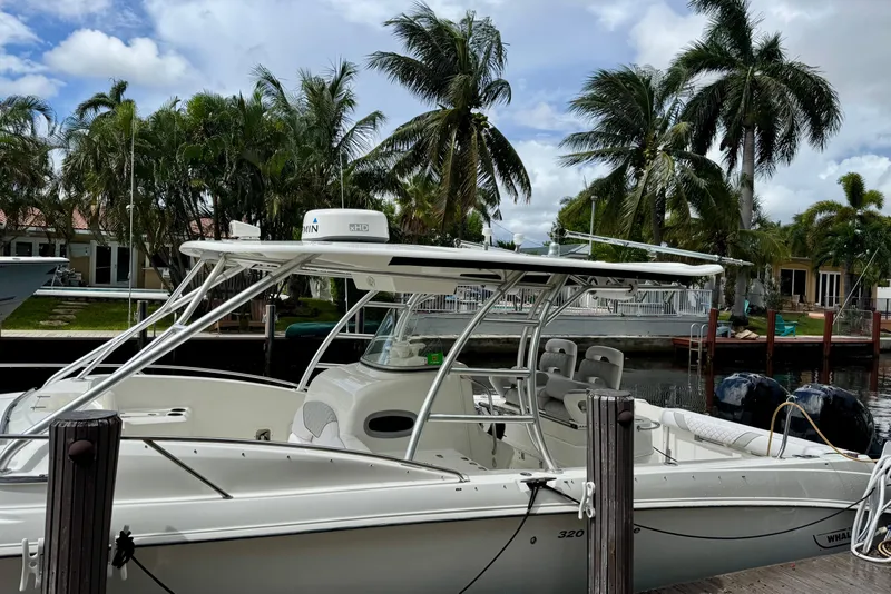 Slide: The Image of 2006 Boston Whaler 320 Outrage Cuddy Cabin docked, surrounded by palm trees and waterfront homes. - 2