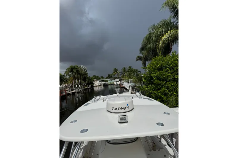 Slide: The Image of 2006 Boston Whaler 320 Outrage Cuddy Cabin docked near lush greenery and palm trees. - 3