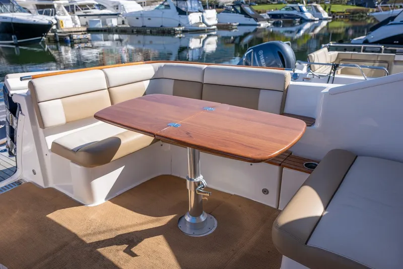 Slide: The Image of 2014 Tiara Yachts 3100 Coronet interior with seating and table, docked at marina. - 13