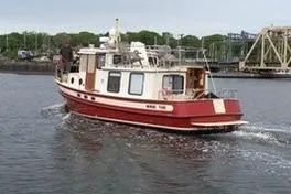 Slide: The Image of Red and white 1996 Nordic Tug 32 cruising on a calm river near a bridge. - 1