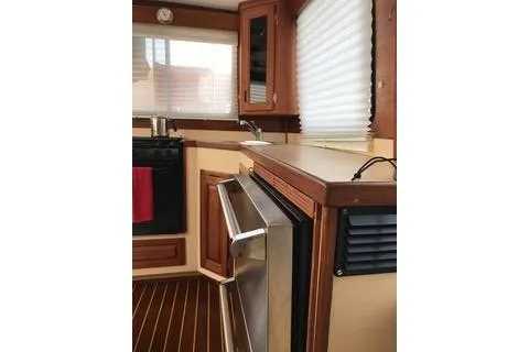 Slide: The Image of Interior of a 1996 Nordic Tug 32, featuring a compact kitchen with wooden cabinetry. - 17